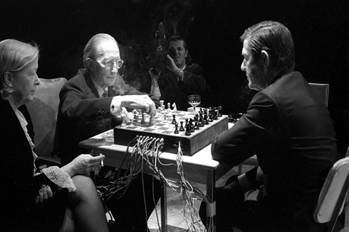 Marcel Duchamp plays white, John Cage plays black, on a chessboard modified to generate tones depending on where the chess pieces are. Toronto, 1968. Teeny Duchamp at far left, cameraman in the background.  This was a performance.